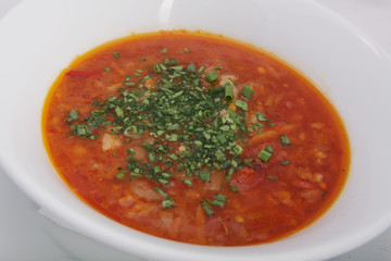 borsch (red soup) with fresh green onions close-up in a white plate