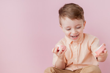 Happy little boy with a gift . Photo isolated on pink background. Smiling boy holds present box. Concept of holidays and birthday