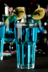 Cocktail blue lagoon in a cocktail glass with lemon and mint on a brown dark table in a bar. bar accessories.
