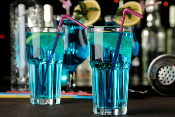 Cocktail blue lagoon in a cocktail glass with lemon and mint on a brown dark table in a bar. bar accessories.