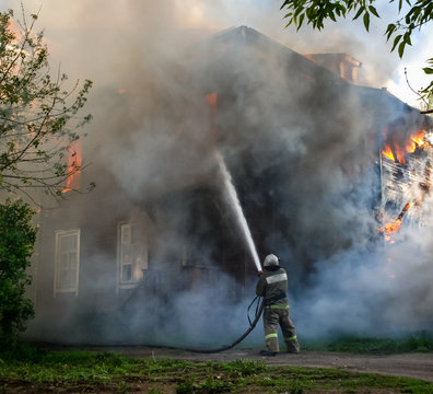 Fireman Works On The Fire. Old Wood House Burns