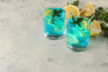 Cocktail blue lagoon in a cocktail glass with lemon and mint on a bright table in the bar. cool summer cocktail