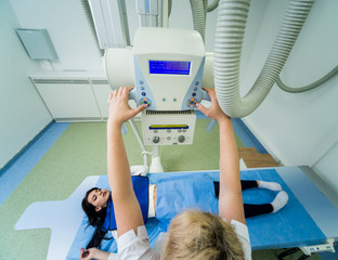 Radiologist and patient in a x-ray room. Classic ceiling-mounted x-ray system.