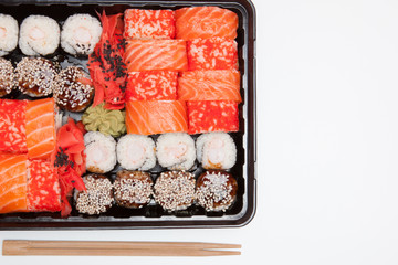 Big sushi set ib black plastic box on white background, top view close up, copy space