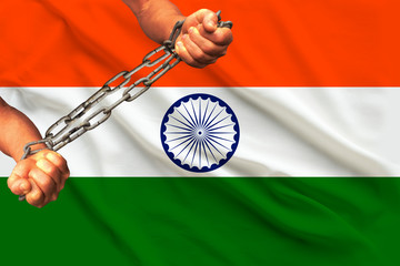 men's hands chained in heavy iron chains against the background of the flag of India on a gentle...