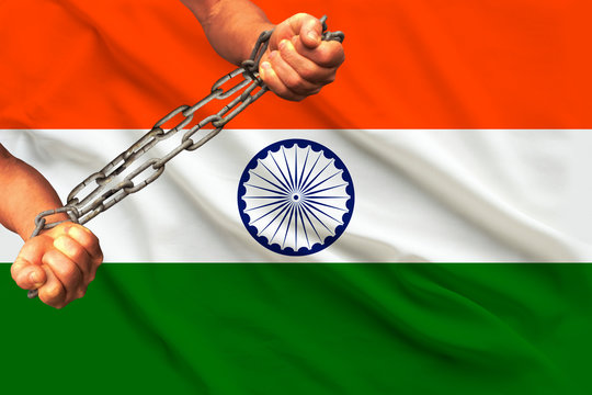 men's hands chained in heavy iron chains against the background of the flag of India on a gentle silk with folds in the wind, the concept of the human rights movement