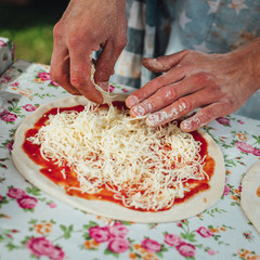 Male chef preparing dough for pizza in outdoor market. Street food.