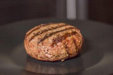 big grilled beef or pork chop cooked on a black plate to make a burger.