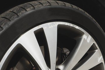 Car wheel closeup. Damaged alloy rim with black thin tire. Bad driver concept. Sunny day.