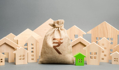 Money bag with a sign indian rupee (rupiah) and wooden houses. The concept of real estate market....