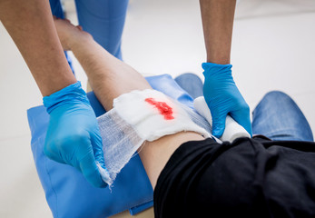Nurse dressing wound for patient's hand with deep skin cutting.