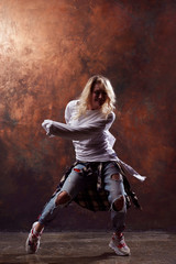 Fototapeta na wymiar Photo of young dancing blonde in torn jeans on brown background