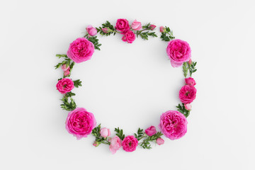 Floral wreath made of pink roses and green branches on a white background.