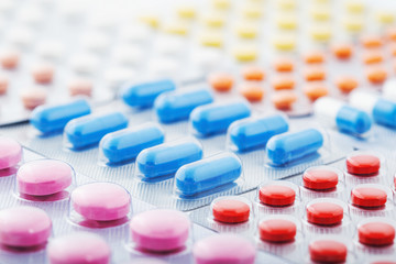 Heap of medical pills in white, blue and other colors. Pills in plastic package. Concept of...