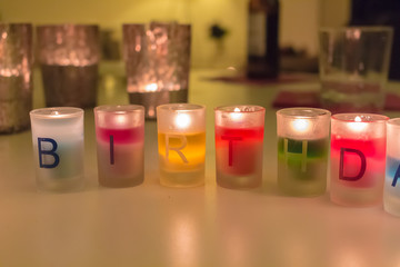 Fototapeta premium Colorful Birthday Candles and other decoration on a white table on a party evening