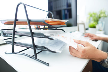 Close-up of a man's hand pulling files from office shelves. White collar job, digital shopping,...