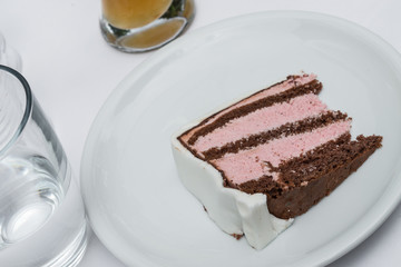 Ein Stück Hochzeitstorte auf einem Teller und dazu ein Glas Wasser und ein Weißbier