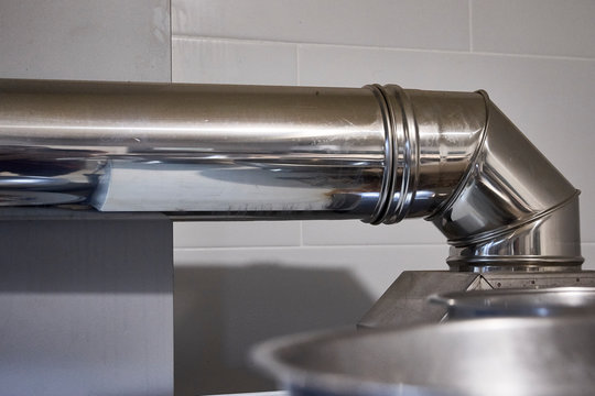 Steel stainless aluminum silver big rounded oven pipes heat steam ventilation protection. Professional clean modern industrial restaurant kitchen.