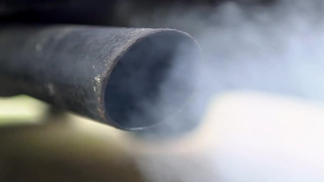 Close-up combustion fumes coming out of car exhaust pipe which strongly of white smoke. Poisonous carbon monoxide from vehicle on road, air pollution concept. Fume emissions in the traffic-Dan