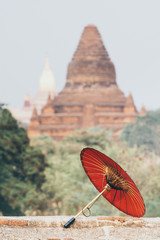 Traditional Burmese red umbrella with Ananda temple on background in Bagan, Myanmar