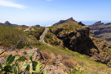 Wide panorama of the Teno mountains gorge serpentine road to the village of Maska in Tenerife with cacti in the foreground. Canary Islands. Spain.