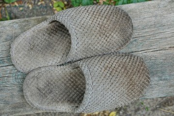 two old gray dirty slipper stand on a wooden board