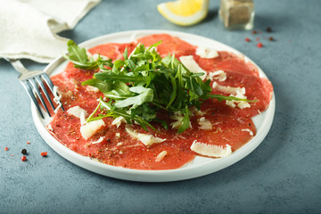 Homemade beef carpaccio with cheese and arugula