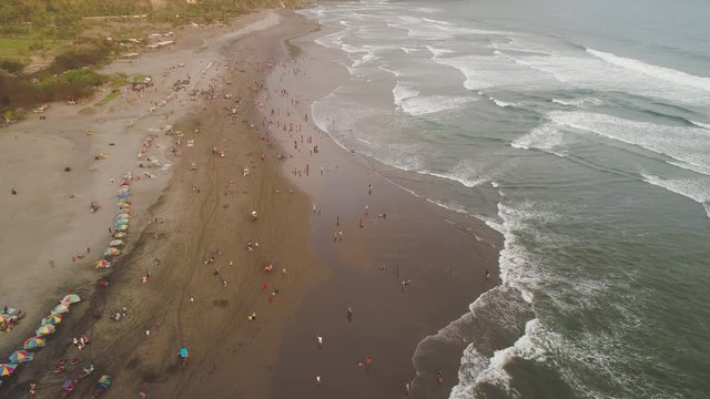 sandy beach parangtritis near ocean with big waves, people in tropical resort at sunset. Yogyakarta, Indonesia. aerial view seascape, ocean and beautiful beach. Travel concept. Indonesia, java