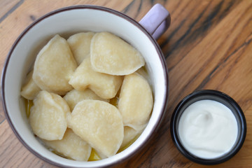 Вoiled dough and sour cream in an enamel bowl on the table