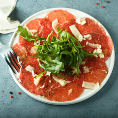 Homemade beef carpaccio with cheese and arugula
