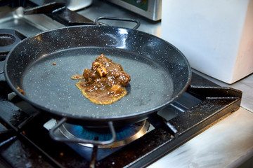 Solid broth paella foundation preparation. Heating in a pan.