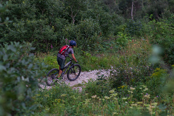 Fototapeta premium Cyclist in Red Riding the Bike on the Autumn Rocky Trail at Sunset. Extreme Sport and Enduro Biking Concept