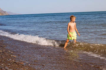 child swimming in the sea, a little boy running along the coast