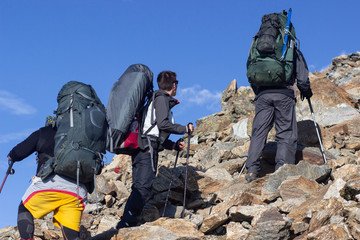 A group of tourists with large backpacks are on thunderstorm to the mountain