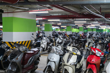 Motorcycles and scooters park in the underground basement parking of the apartment