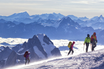 A group of mountaineers climbs to the top of a snow-capped mountain