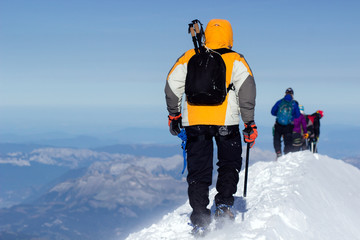 A group of mountaineers climbs to the top of a snow-capped mountain