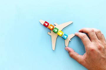 Transportation concept image, man's hand holding toy airplane with people icons over blue background. Travel and leadership idea