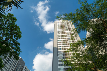 Modern condominium building with green leaves on foreground. Green city concept