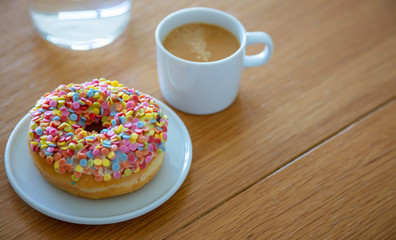 Doughnut and coffee cup on wood. Close up view