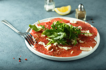 Homemade beef carpaccio with cheese and arugula