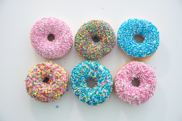 Doughnuts with colorful decoration on white color background. Top view