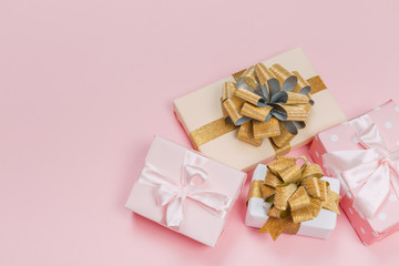 Gift box wrapped in pastel  paper with pink ribbon on pink surface. Top view  with copy space.