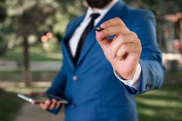 Businessman holds pen and points into copy space. Man with lap top and pen in the hand.