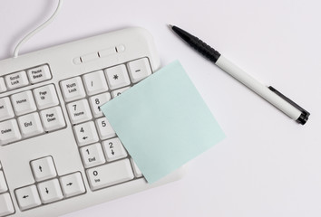 White pc keyboard with empty note paper above white background.