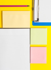 Colored empty papers with copy space on the yellow background table.