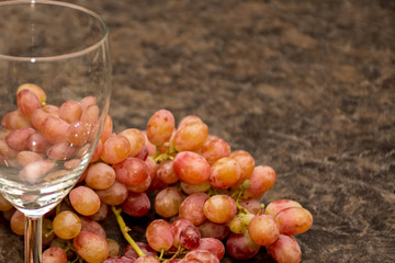 Red ripe grapes and a wine glass on dark marble background