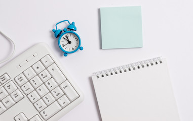 White pc keyboard with empty note paper and pencil above white background.