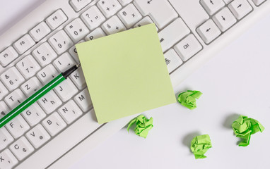 Square empty green note paper with pencil on the white background and pc keyboard.