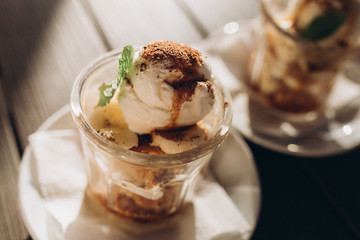 Ice ceam with chocolate and mint in glass cup on wooden table in street cafe. Food, dessert concept
